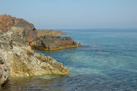 Rochers de diverses couleurs qui plongent dans une mer limpide